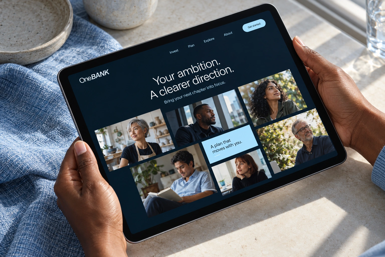 OneBANK investor website on a landscape iPad held by two hands above pale stone and blue linen, with a navy interface and original portrait imagery